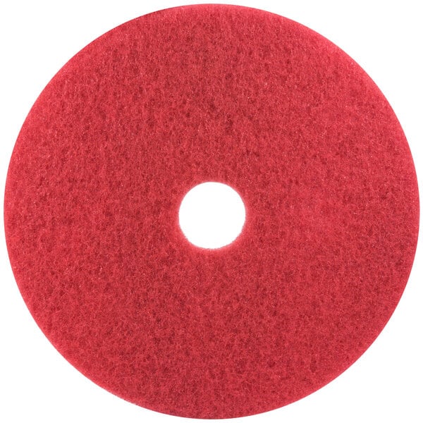 A red 3M buffing pad for floors with a hole in the middle.