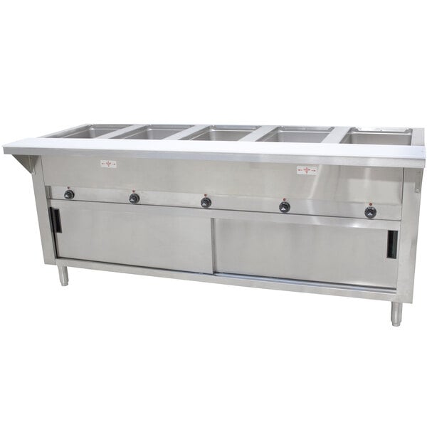 An Advance Tabco stainless steel hot food table with enclosed base and sliding doors on a counter in a large commercial kitchen.