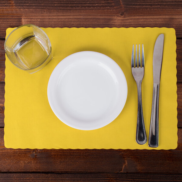 A white plate with a fork and knife on a yellow Hoffmaster scalloped paper placemat.