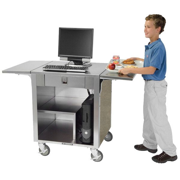 A boy standing next to a Lakeside cash register stand with a laptop on the counter.