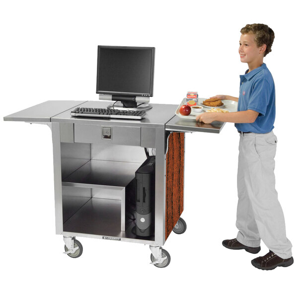 A young boy standing next to a Lakeside cash register stand with a computer on it.
