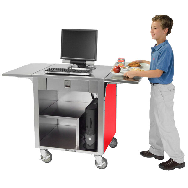 A boy standing next to a Lakeside stainless steel cash register stand with a red laminate finish.