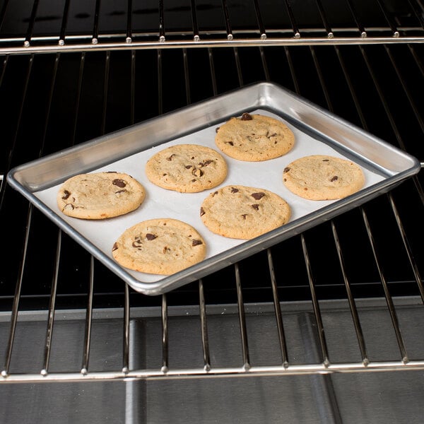 A Chicago Metallic aluminum sheet pan with a tray of cookies baking in an oven.