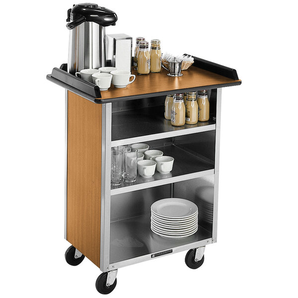 A Lakeside stainless steel beverage service cart with light maple laminate shelves holding coffee and tea cups.