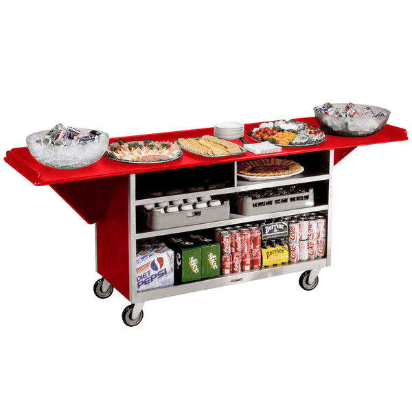 A red and silver Lakeside beverage service cart full of food and drinks on a table outdoors.