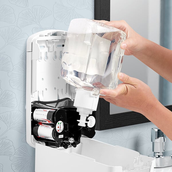 A person pouring GOJO foaming hand soap into a dispenser.