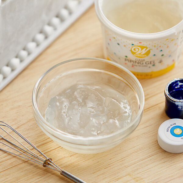 A clear bowl of Wilton Clear Piping Gel next to a whisk and a bowl of gel.