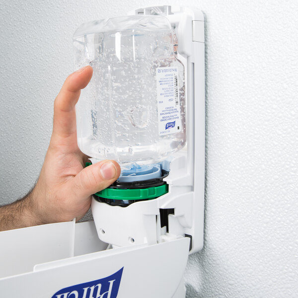 A hand using Purell hand sanitizer from a plastic bottle.