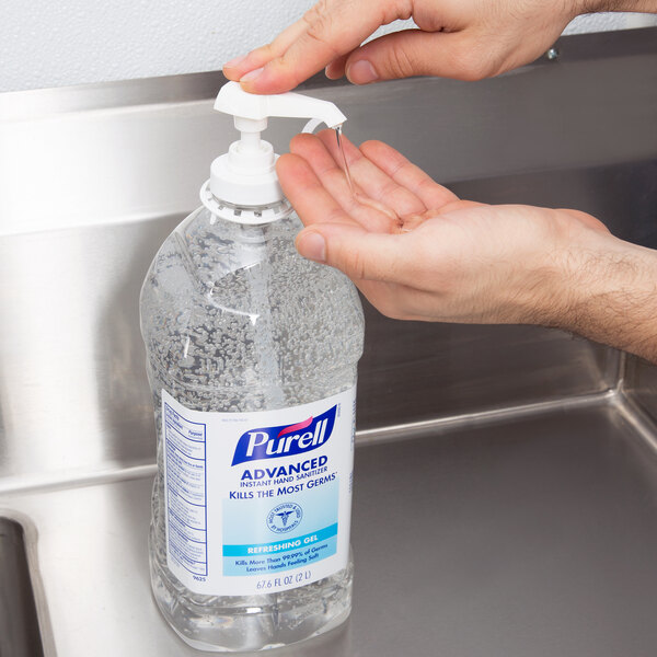 A hand holding a bottle of Purell Advanced hand sanitizer.