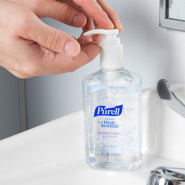 A person using a pump dispenser to dispense Purell hand sanitizer.