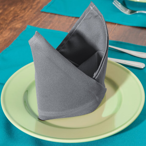 A folded gray Intedge cloth napkin on a plate.