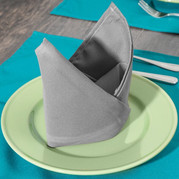 A folded Intedge gray cloth napkin on a plate with a fork.