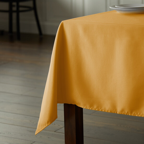 A rectangular table with a yellow Intedge tablecloth.