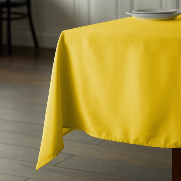 A yellow Intedge square tablecloth on a table.
