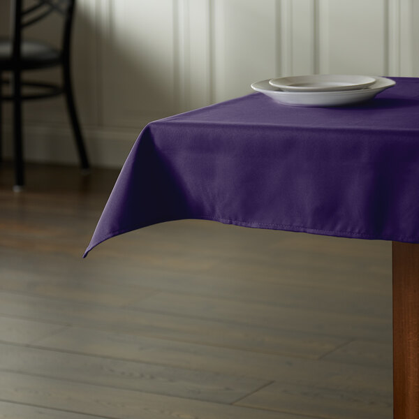 A table with a purple Intedge tablecloth and a plate on it.