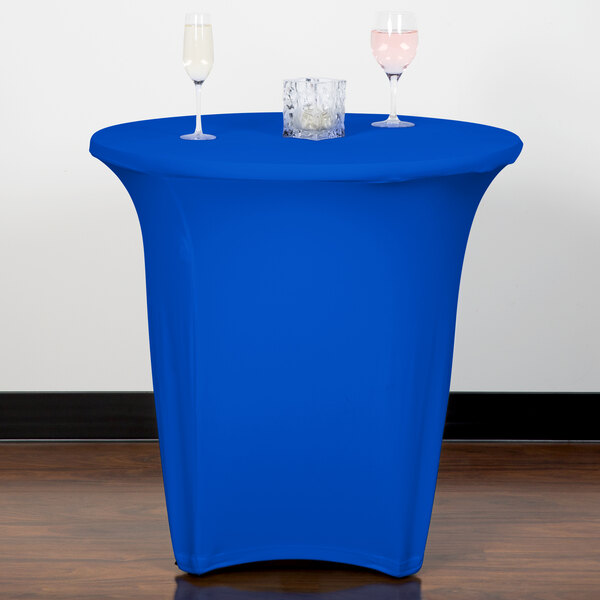 A blue Snap Drape spandex table cover on a round table with two wine glasses on it.