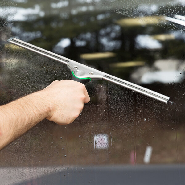 A hand holding a Unger ErgoTec window squeegee on a window.