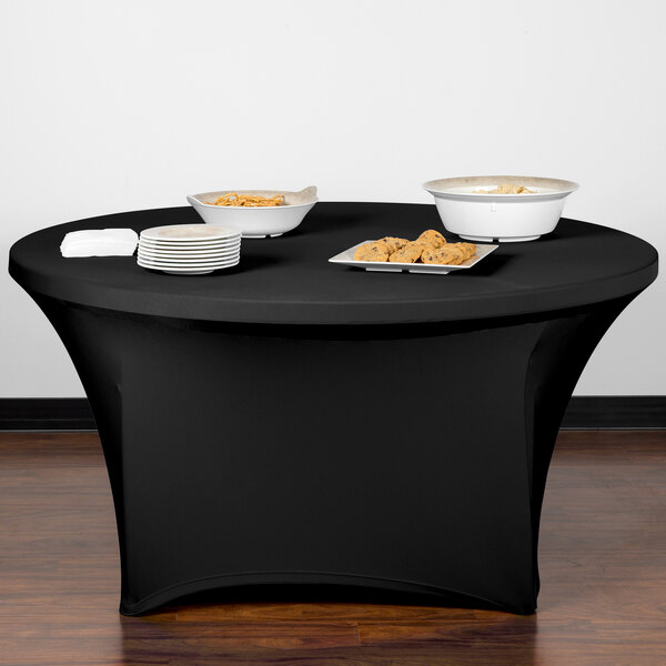 A black Snap Drape Contour spandex table cover on a table with plates of food.