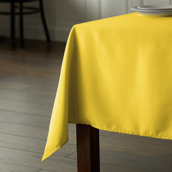 A table with a yellow Intedge tablecloth on it.