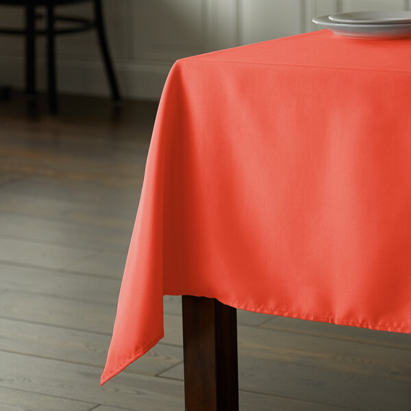 An orange rectangular table with an Intedge orange polyester tablecloth.
