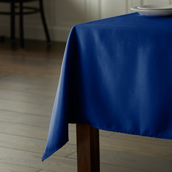 A royal blue Intedge rectangular table cloth on a wooden table.