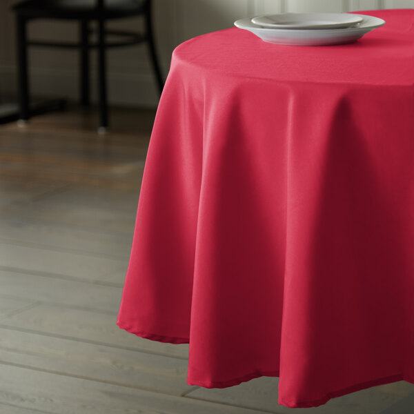 A hot pink Intedge round tablecloth on a table with a plate on it.