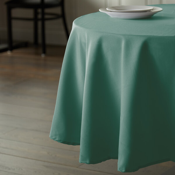 A table with a teal Intedge tablecloth and a white plate on it.
