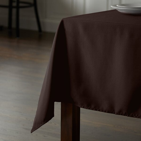 A brown Intedge 100% polyester tablecloth on a wooden square table.