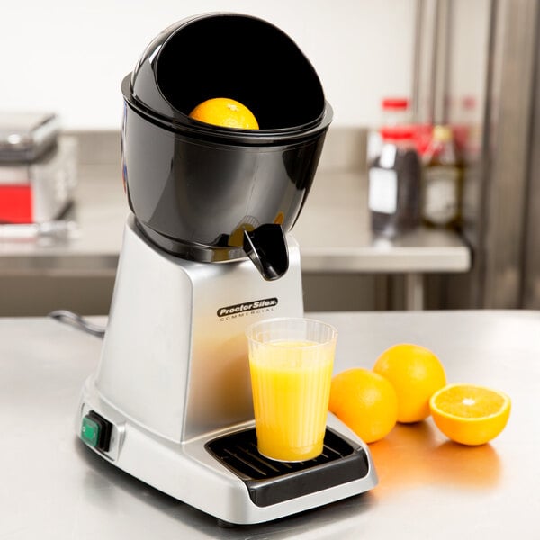 A Proctor Silex electric citrus juicer on a counter with oranges.