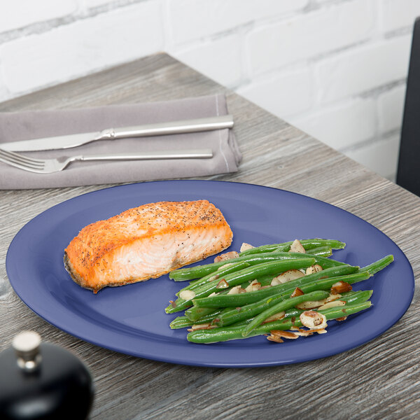 A peacock blue oval melamine platter with salmon and green beans on it.