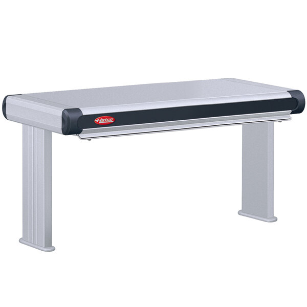 A grey rectangular table with black and white trim and a Hatco Glo-Ray double infrared strip warmer on top.