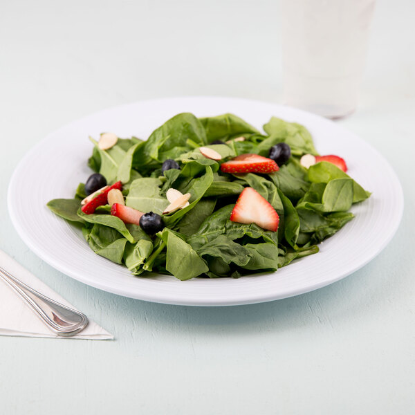 A Minski white melamine plate with a salad of strawberries and blueberries.