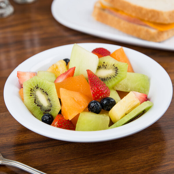 A white melamine bowl filled with fruit on a table.