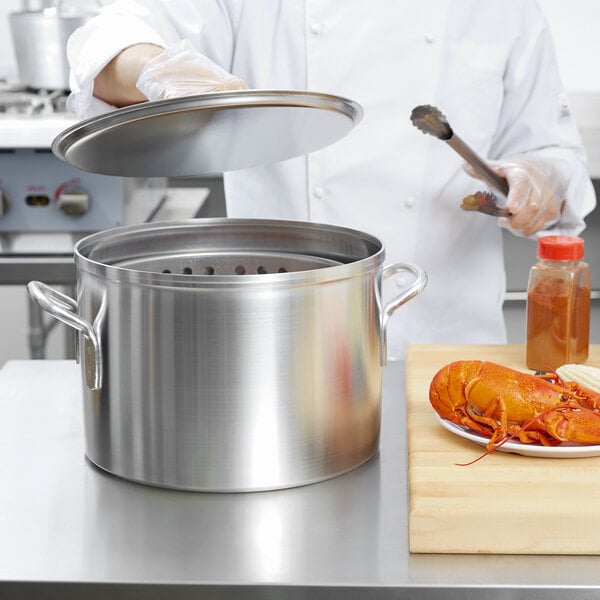 A chef using a Vollrath silver boiler and fryer pot to cook a lobster.