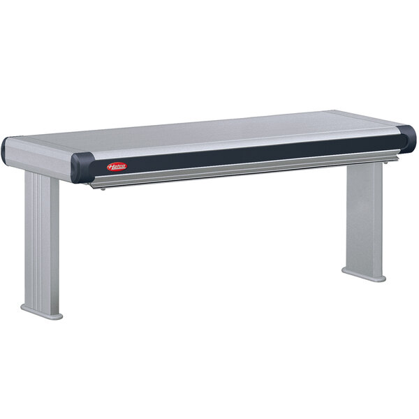 A grey rectangular Hatco strip warmer above a stainless steel table with black and red top.