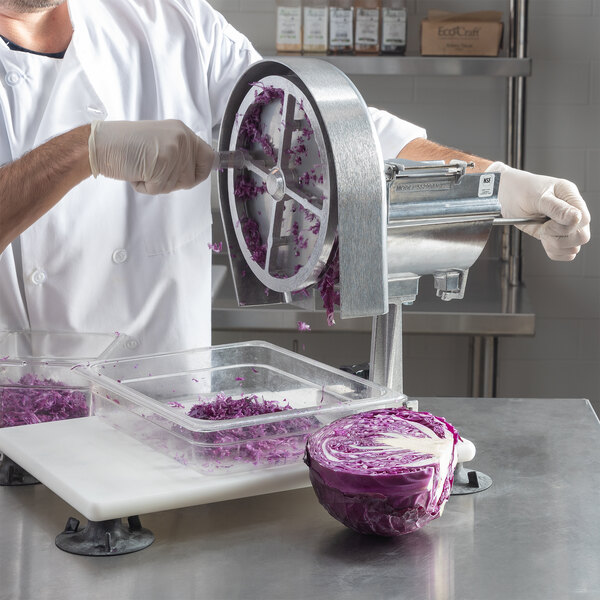 A person in a white coat and gloves using a Nemco Easy Slicer to cut purple cabbage.