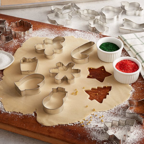 A metal Wilton holiday cookie cutter set on a table with cookie dough.