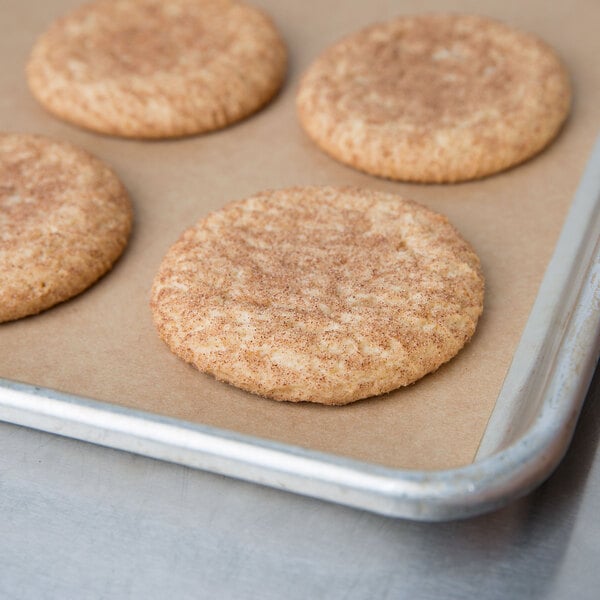 A Baker's Mark parchment paper lined tray of cookies with a round brown cookie on it.