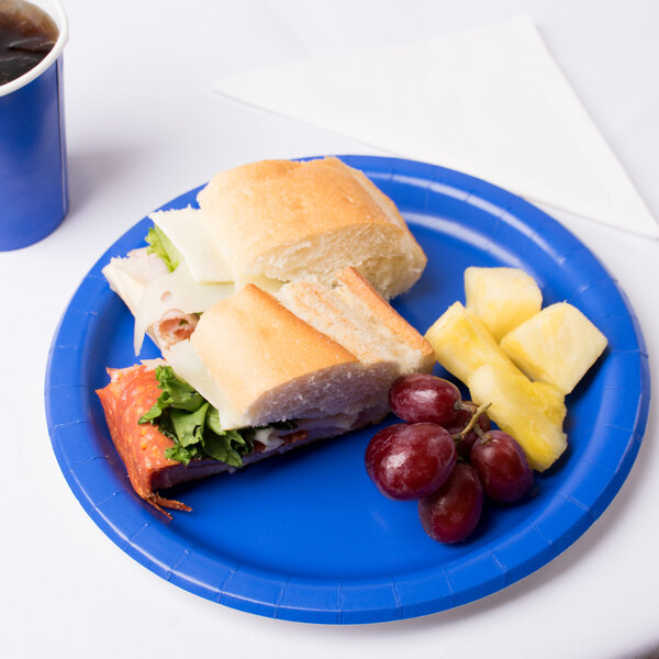A sandwich and fruit on a Creative Converting cobalt blue paper plate.