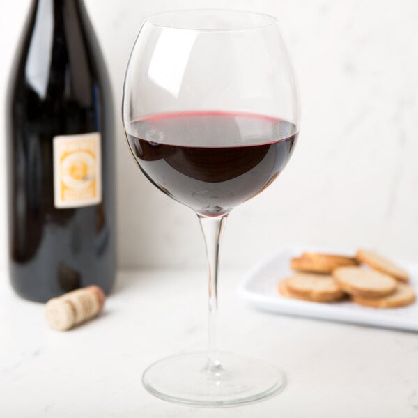 A Reserve by Libbey red wine glass next to a bottle of red wine and crackers.