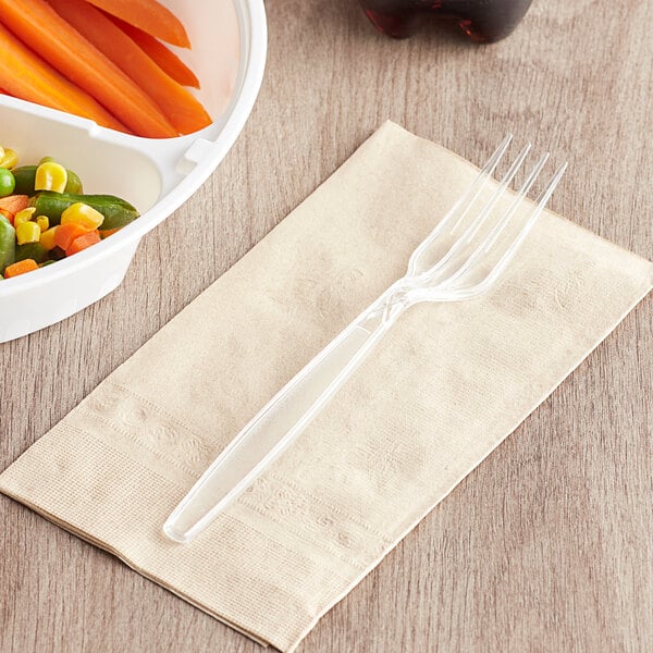 A clear plastic Visions heavy weight fork on a napkin next to a bowl of carrots and corn.