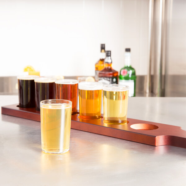 A Libbey Straight Sided Tasting Glass of beer on a mahogany flight paddle.