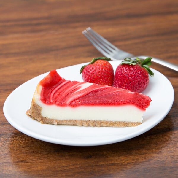 A slice of cheesecake with strawberries on a 10 Strawberry Street white oval bone china plate.