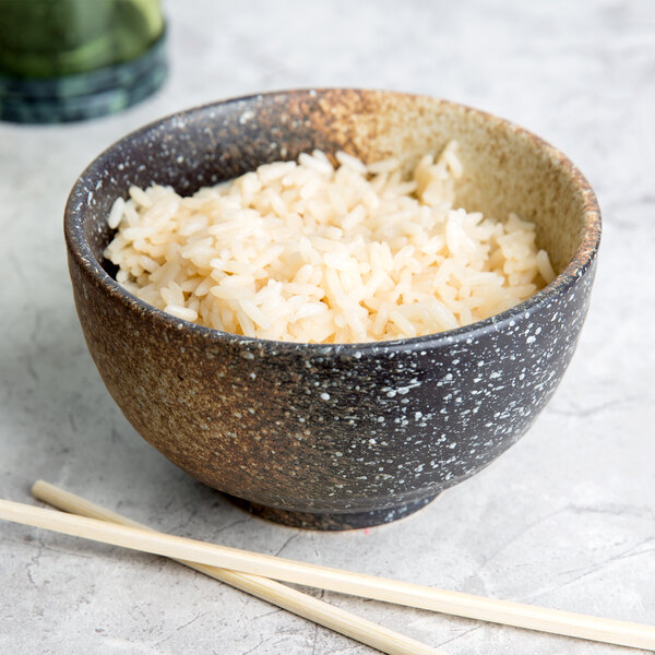 A 10 Strawberry Street Whittier stoneware rice bowl filled with rice with chopsticks next to it.