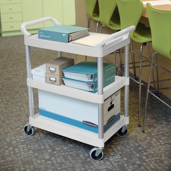 A white Rubbermaid utility cart with three shelves of boxes and folders.