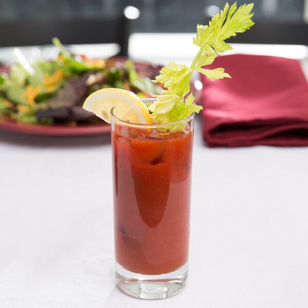 A close up of an Arcoroc Islande highball glass with a bloody mary and a lemon garnish on a table with a salad