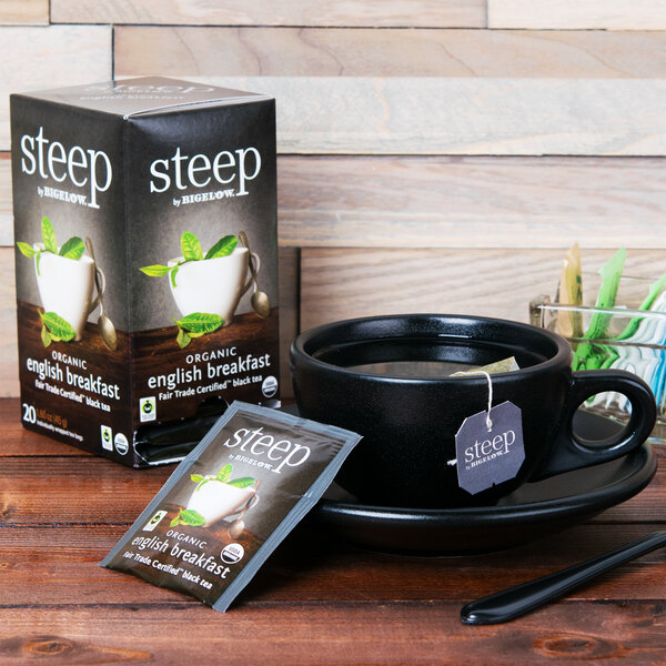 A white cup of Steep By Bigelow Organic English Breakfast tea next to a box of tea.