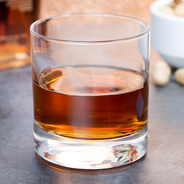 An Arcoroc Islande old fashioned glass filled with brown liquid on a table.