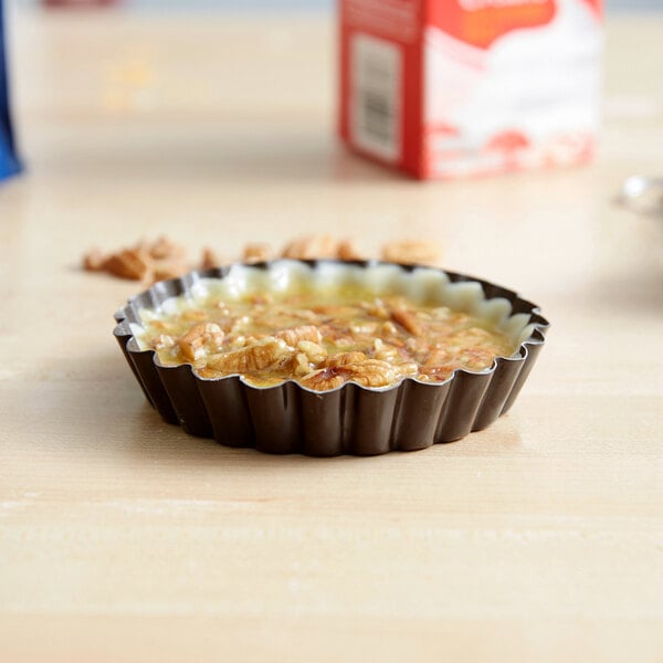 A Gobel fluted non-stick tart pan on a table with a quiche in it.