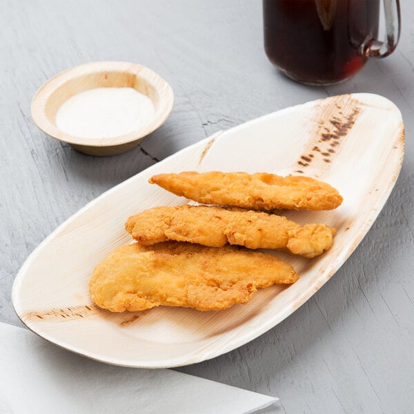 An EcoChoice oval palm leaf tray with fried chicken on a table.